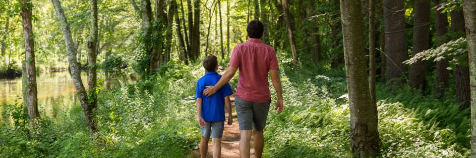 A father and son walk alongside the River at Old Sturbridge Village