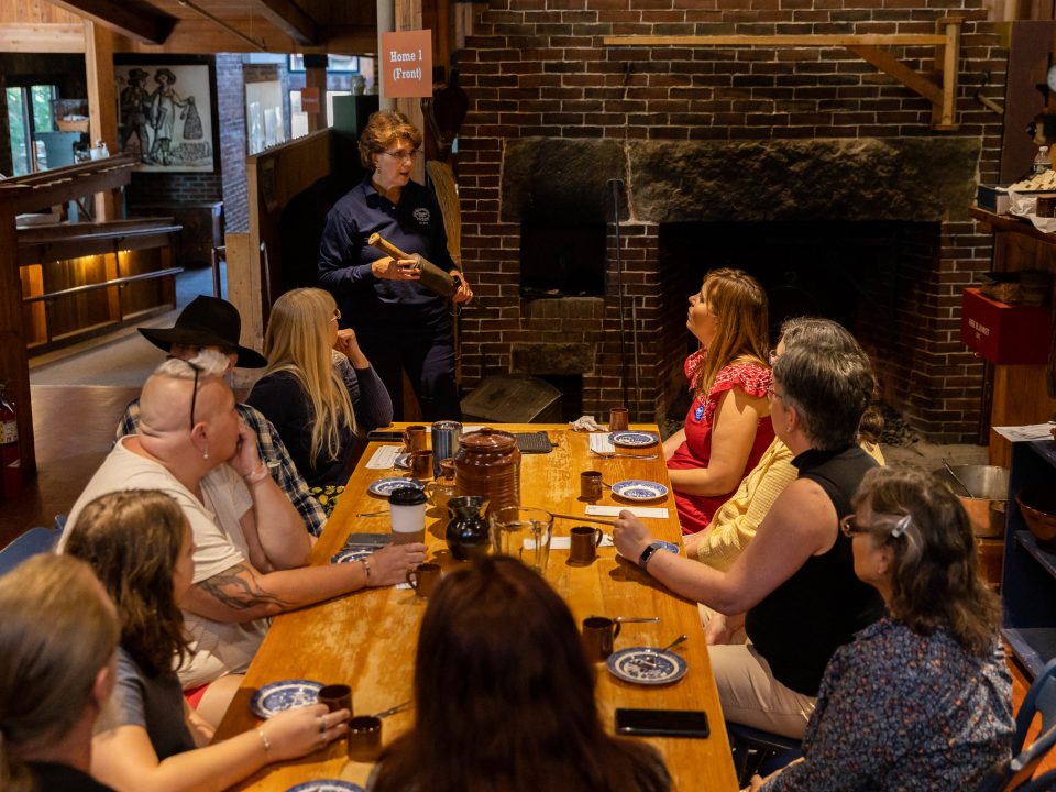 A group of adults sit at a table learning about hearth cooking