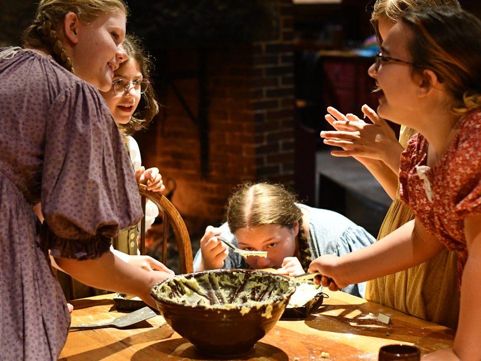 Elementary age kids work together to bake over the hearth