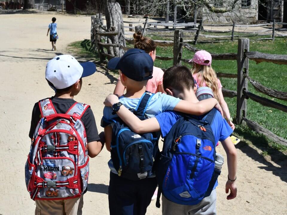 Three students walk side by side down the road